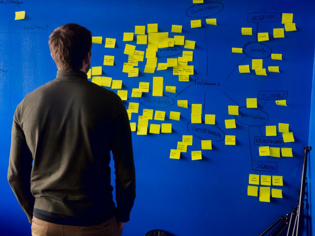 man looking at puzzle wall of yellow stickies 