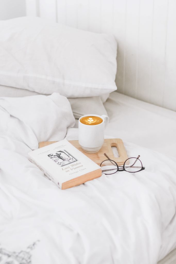 coffee, glasses and book on bed